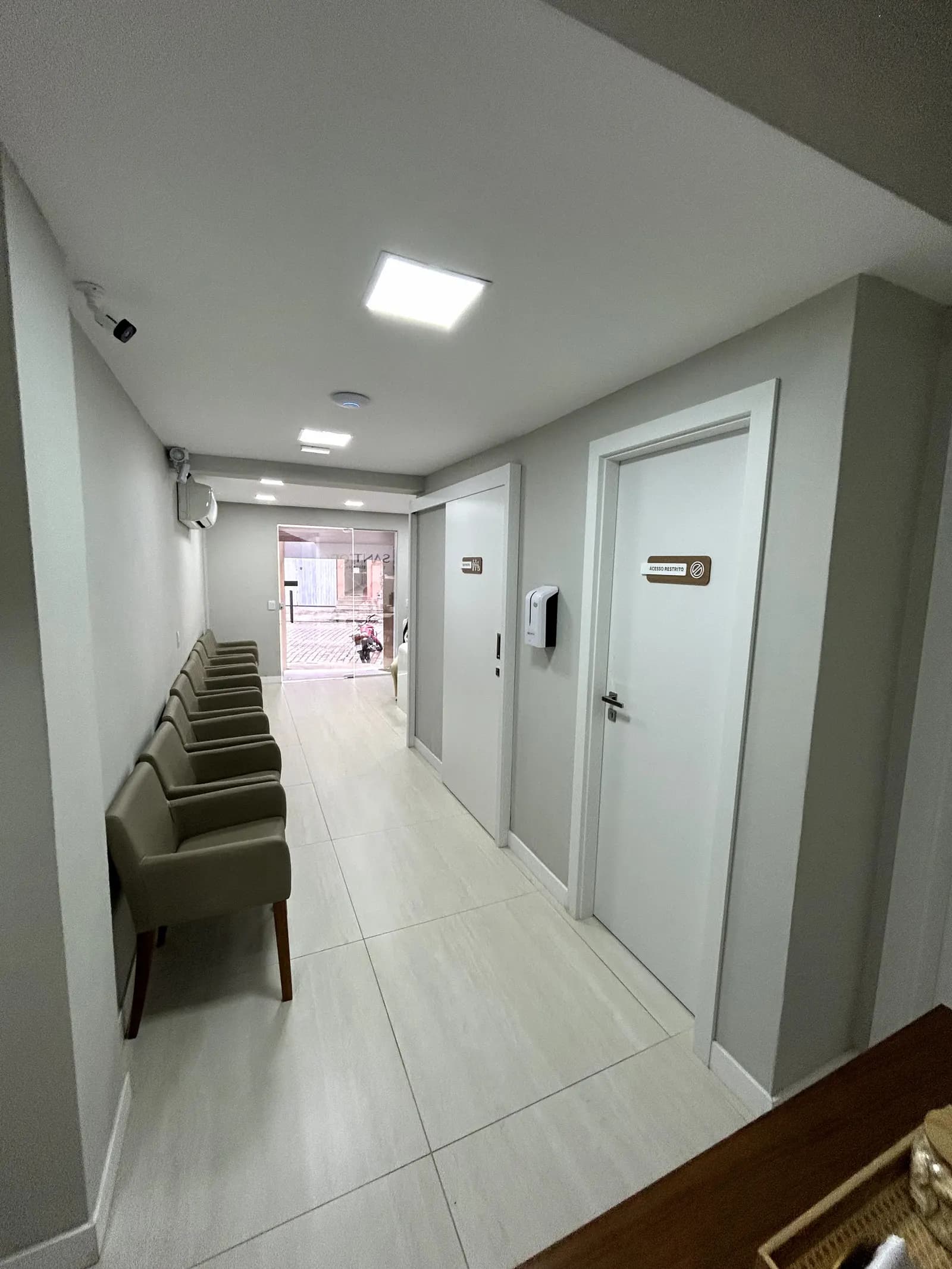 Foto oficial do corredor e área de espera da Clínica Santoro, com consultórios à direita.